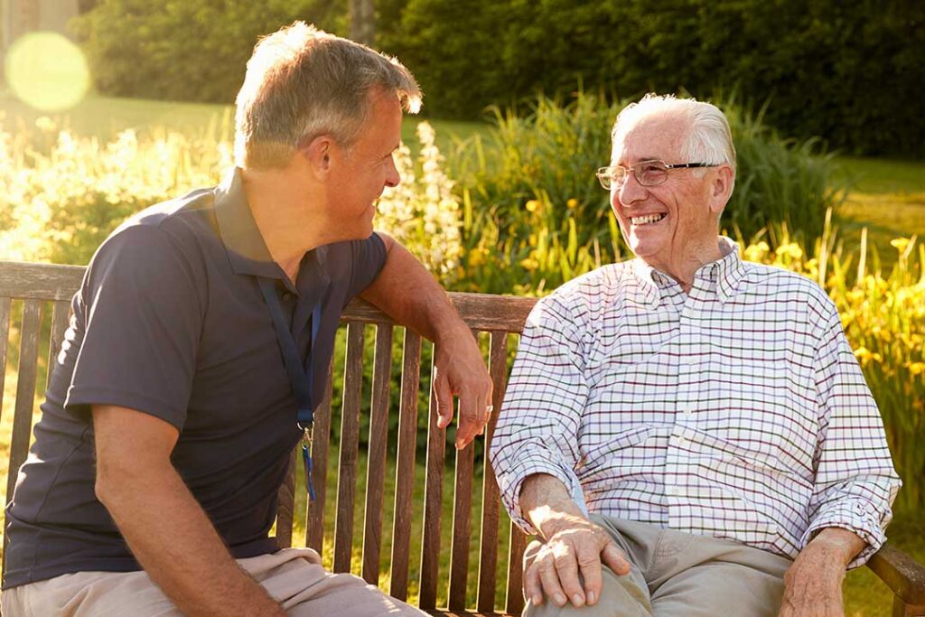 Resident arranging family photos and a comfortable chair in a bright assisted living apartment.