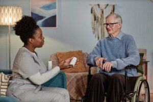 Older adult arranging family photos in a comfortable assisted living room while a relative offers support.